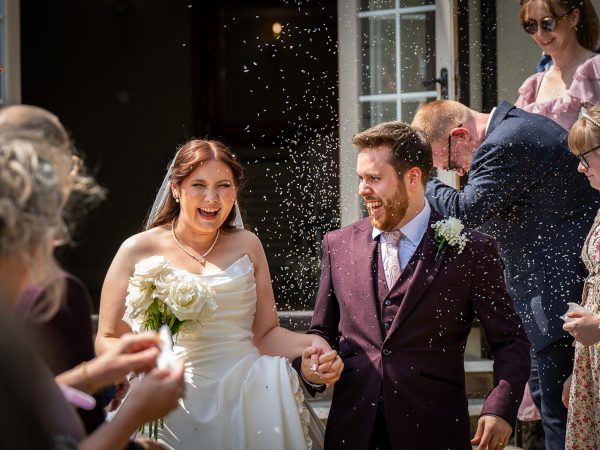 Bride and groom walking through confetti with their guests – Adam and Abbey’s wedding at Tottington Manor