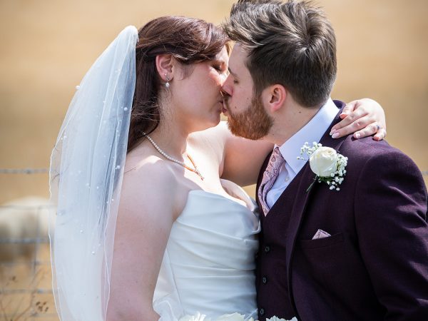 Adam and Abbey’s wedding at Tottington Manor – couple kissing in the fields