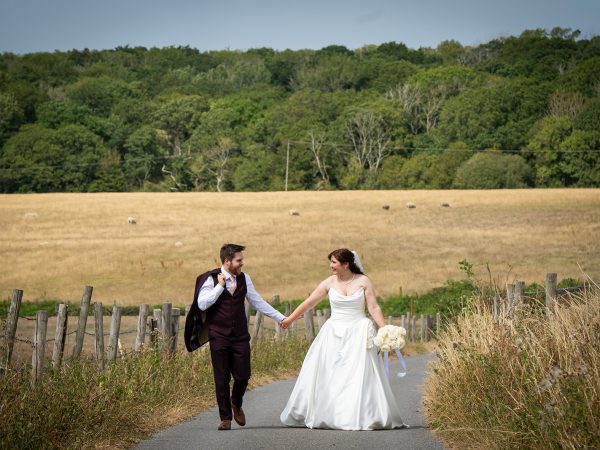 Adam and Abbey’s wedding at Tottington Manor – couple walking on a lane through the Downs