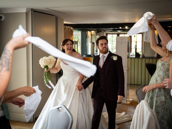 Adam and Abbey’s wedding at Tottington Manor – guests waving napkins as the couple enter