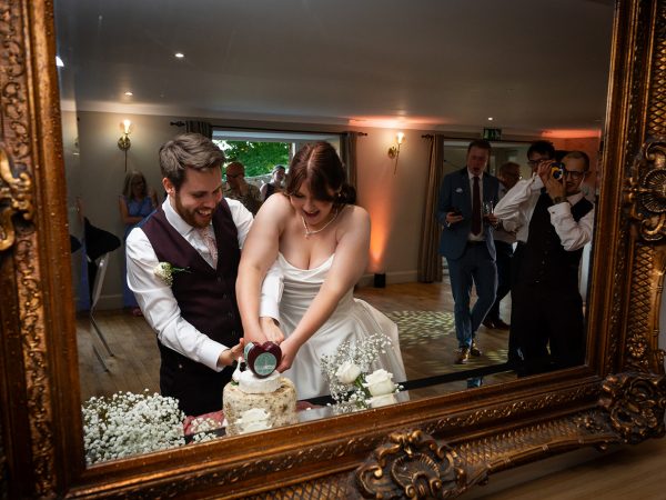 Adam and Abbey’s wedding at Tottington Manor – cutting the cake reflected in a mirror