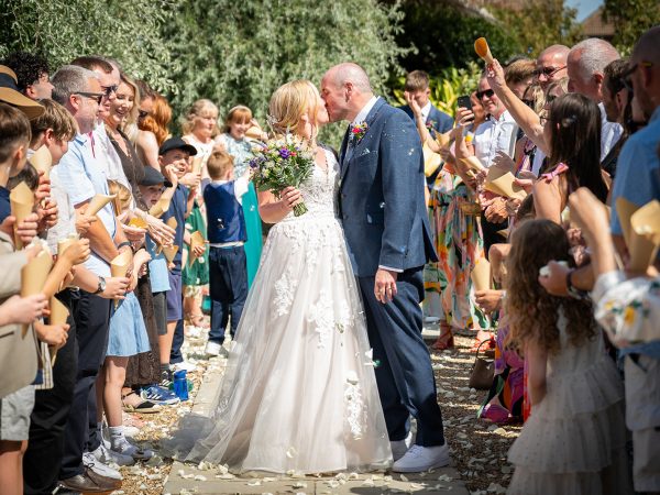 Holly and Andy’s wedding at Field Place – a kiss in the confetti line