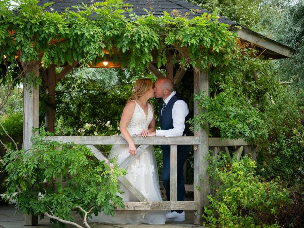 Holly and Andy’s wedding at Field Place – bride and groom in the garden pergola